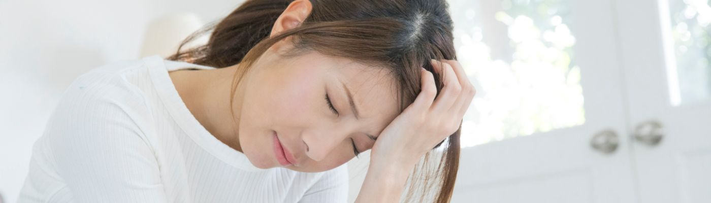 具合が悪く頭を抱える女性